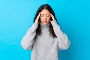 Donna con mal di testa su sfondo azzurro