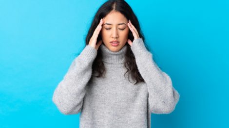 Donna con mal di testa su sfondo azzurro