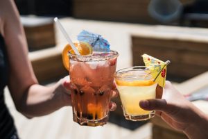 Dettaglio di due persone che fanno cin cin con due bicchieri di cocktail ghiacciati