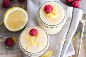 due barattolini di dolce al latte ripresi dall'alto e guarniti con scorze di limone e lamponi