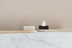 due spazzolini da denti manuali in legno. Uno dei due, sulla destra, ha sopra un poco di dentifricio