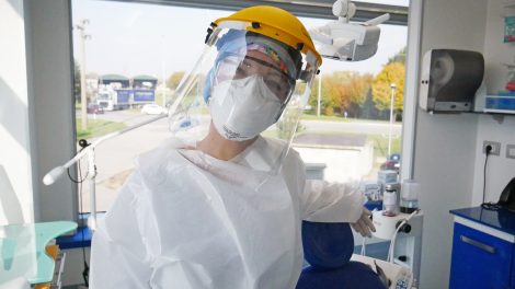 Una igienista dentale di Amicodentista sorride sotto tutti i dispositivi di protezione individuale necessari per la prevenzione della diffusione del covid 19: visiera, mascherine, camici, guanti etc