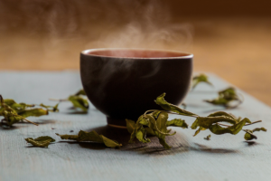 Una tazza di tè, circondata da foglie di menta