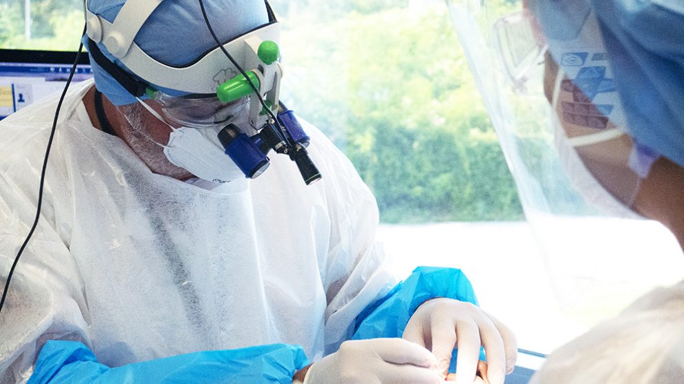 Il dottor Maurizio Pedone al lavoro mentre opera un paziente assistito da una ASO (assistente di studio odontoiatrico)