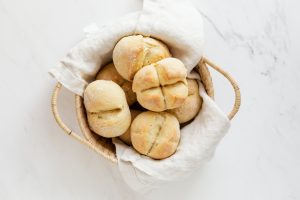 Un cestino di vimini contenente pane bianco, poggiato su una lastra di marmo bianco