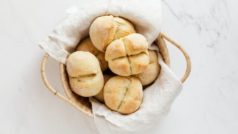 Un cestino di vimini contenente pane bianco, poggiato su una lastra di marmo bianco
