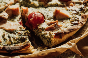 Una foto di una torta salata a base di spinaci e formaggio, decorata con alcuni pomodorini