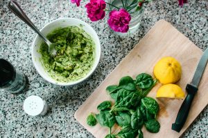Una ciotola di pesto, affiancata da un tagliere con spinaci