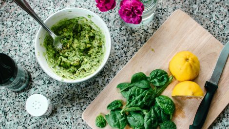 Una ciotola di pesto, affiancata da un tagliere con spinaci