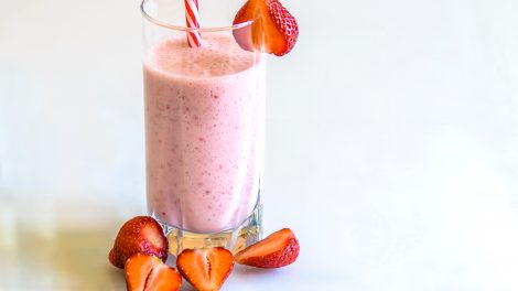 Un frullato / milkshake di fragole e banana all'interno di un bicchiere con cannuccia e fragole