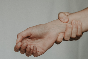 Dettaglio fotografico di una persona che si tiene il polso dolorante con l'altra mano