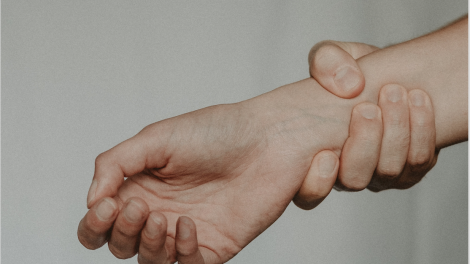 Dettaglio fotografico di una persona che si tiene il polso dolorante con l'altra mano