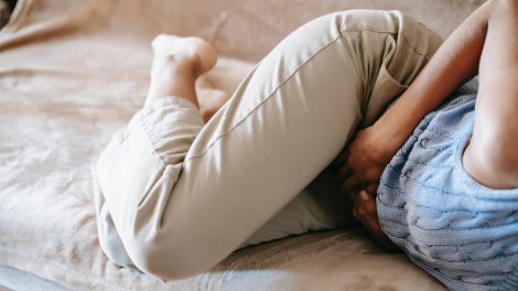 una donna che ha dolore si tiene la pancia sdraiata su un divano