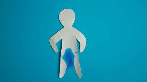Un omino di carta con una macchia di liquido a livello della vescica