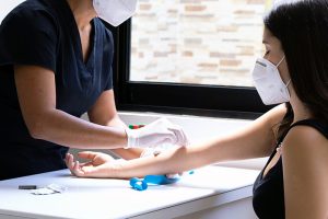 Un'inferiera effettua un prelievo del sangue a una paziente. Entrambe indossano la mascherina ffp2