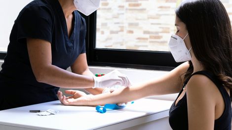 Un'inferiera effettua un prelievo del sangue a una paziente. Entrambe indossano la mascherina ffp2