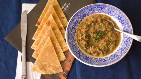 Un piatto di zuppa di lenticchie con a fianco tranci di pane